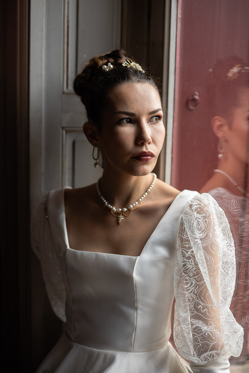 mariée assise devant la fenêtre du chateau style Bridgerton